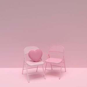a pink chair and a white chair with a heart shaped pillow